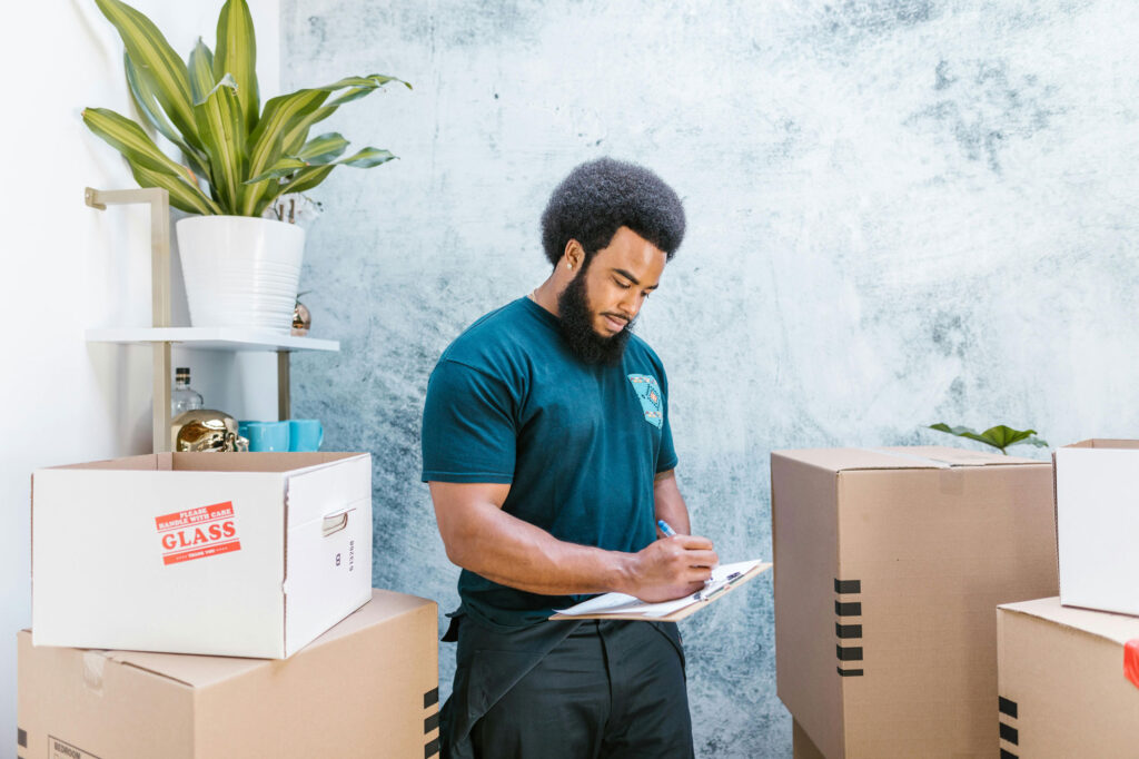 Man holding a clipboard surrounded by moving boxes
