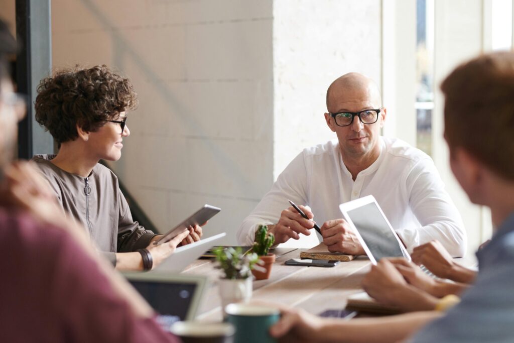 a group of people sit around a table in a bright office